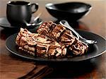 Two slices of chocolate roulade on a black plate