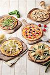 Five different vegetarian pizzas on wooden boards