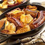 Swiss sausages with apples and onions in an iron pan