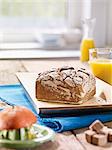 A square loaf of rye bread on a flat wooden tray