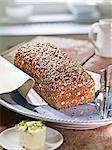 A whole loaf of wholemeal rye bread with seeds on a plate