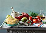 An arrangement featuring grilled corn cobs, tomatoes, peppers, lemons and oil