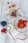 A healthy breakfast: muesli with fresh fruits and milk, strawberries, raspberries, blueberries on a wooden table