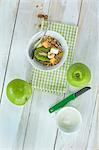 A healthy breakfast: muesli with fresh fruits, nuts and milk, kiwi, apple and melon on a wooden table