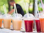 Various juices in plastic cups at a market stall