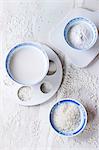 Bowls of rice milk, rice flour and rice grains on a marble surface (seen from above)