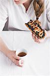 A woman with an toasted open sorrel sandwich and a cup of tea