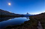 Full moon and Matterhorn illuminated for the 150th anniversary of the first ascent, reflected in Lake Stellisee, Zermatt, Canton of Valais, Swiss Alps, Switzerland, Europe