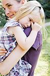 Mid adult woman carrying upset daughter in park
