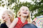 Two young sisters playing on inflatable in park