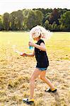 Girl waving bubble wand and making bubbles in park