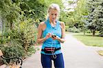 Mature woman choosing smartphone music whilst training in park