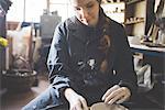 Front view of young woman sitting at pottery wheel looking down making clay pot