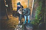 Couple using tongs to remove clay pots from fire, smiling