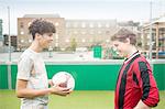Two young men playing football on urban football pitch