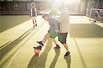 Group of adults playing football on urban football pitch