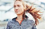 Portrait of female runner with flyaway hair on city footbridge