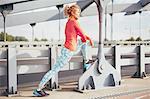 Young female runner warming up on city footbridge