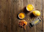Overhead view of yellow raw juice with grated lemon and carrot on wood grain pattern background