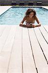 Girl in swimming pool reading smartphone texts, Cassis, Provence, France