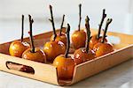 Toffee apples on sticks hardening on wooden tray