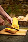 Senior mans hands chopping butternut squash with knife on cutting board