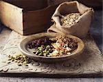 Dried fruits and nuts on wooden plate with burlap sack of oats