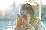 Mature female tourist photographing at Guadalqivir river, Seville, Spain