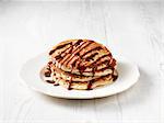 Stack of chocolate chip pancakes drizzled with chocolate sauce