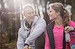 Couple wearing sports clothing holding water bottle sitting face to face smiling