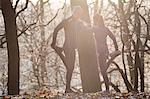 Couple in forest leaning against each other leg raised holding foot stretching