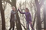 Couple in forest wearing sport clothing doing high five smiling