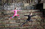 Couple on stone steps in lunge stance arms open stretching, looking away