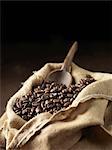 Coffee beans and wooden scoop in woven sack