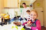 Portrait smiling girl eating apple in kitchen