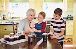 Grandmother canning jam with grandchildren in kitchen