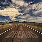 Conceptual image of desert road with the word dreams and arrow