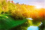 Small calm river in Kamianets Podilskyi with reflection among fresh green grass, trees and bushes
