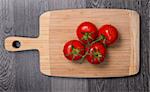 Fresh tomatoes on chopping board on gray table, top view