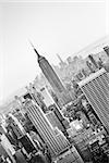 New York City. Manhattan downtown skyline with illuminated Empire State Building and skyscrapers at sunset. Vertical composition. Black and white image.