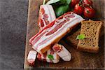 smoked bacon with basil and tomatoes on a cutting board