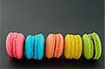 Row of french colorful macaroons on black background.