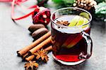 Mulled red wine with apple slices and spices in a glass cup on a Christmas background