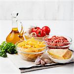 Italian food ingredients: pasta, tomatoes, herbs, minced and spices on wooden background