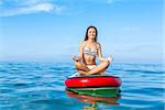 A beautiful woman sitting over a paddle surfboard and relaxing on a beautiful sunny day