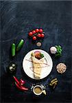 Falafel on a white plate with ingredients laid out on a spiral on a blackboard. View from above