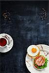 Tea with thyme and breakfast of bacon and eggs on a blackboard. View from above