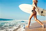 Beauitful young surfer girl running to the waves with her surfboard