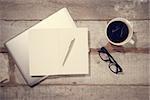 Work desk with laptop computer, planners, pen, eyeglasses and hot coffee cup. Top view rustic wooden table background with copy space in vintage toned.