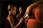 Portrait of young novice monks lighting up candlelight inside a Buddhist temple, low light setting, Bagan, Myanmar.
